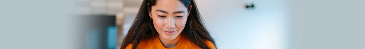 Woman in orange shirt looking at laptop