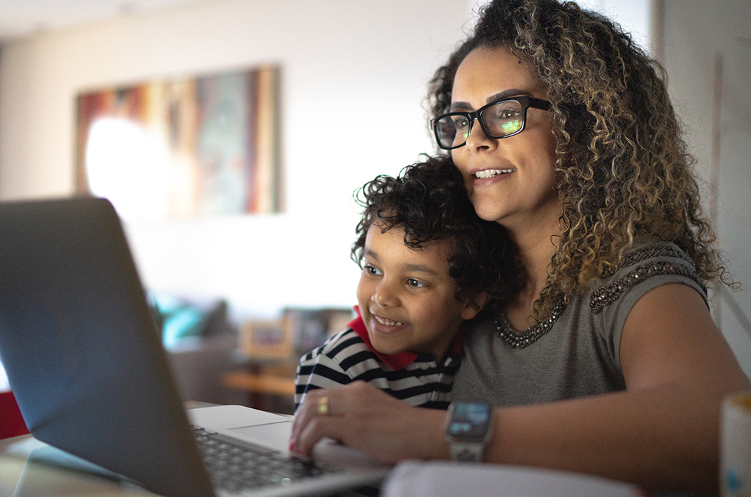 Mature woman working at home, carrying young son